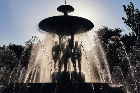 Rostov-on-Don / Russia - August 2018: rays of the setting sun light through the water sprayed by a large dark fountain in the main square of the city on a hot summer dayのeditorial素材