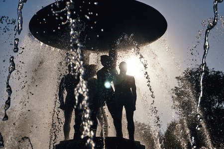Rostov-on-Don / Russia - August 2018: rays of the setting sun light through the water sprayed by a large dark fountain in the main square of the city on a hot summer dayのeditorial素材