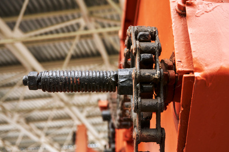 high-quality metal gears and chains on an old tractor of bright orange color in the museum of agricultural equipmentのeditorial素材