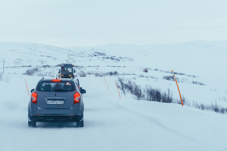 Teriberka, Murmansk region / Russia - February 2018: a convoy of cars moves along a snow-marked highway during a snowstorm on a harsh winter day in the tundraのeditorial素材