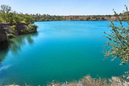 an amazing wild lake without people in a gorge of sand color among the stones and trees with crystal...