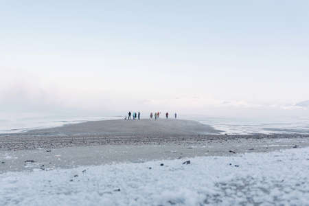 the tide is out on a frosty day in the winter on the North sea and people have come out on a bare bottom covered with iceの写真素材