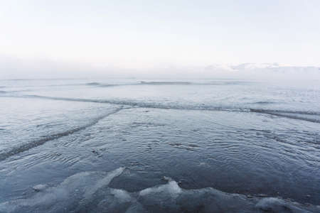 the water freezes and covers the sand with ice and snow on the seashore during the winter frost