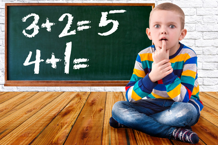 Baby boy solve mathematics examples.The student thinks and feels near the Board.Mathematical tasks.の写真素材