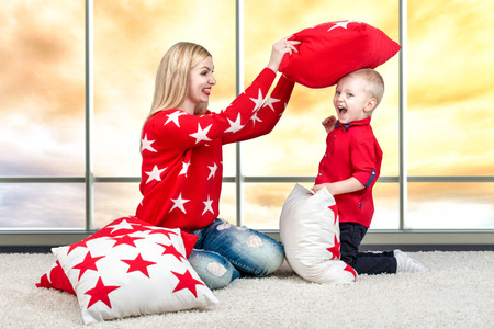 Young mother and little son playing with pillows, pillow fight. The concept of a family holiday.Beautiful pillows to decorate the interior of the house.の写真素材