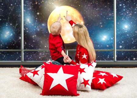 Loving beautiful young mother with young son looking at the sky, the moon, the stars. Sitting on...