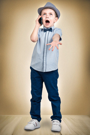 Little boss talks on his mobile phone.Emotional conversation.Shildren's fashionの写真素材