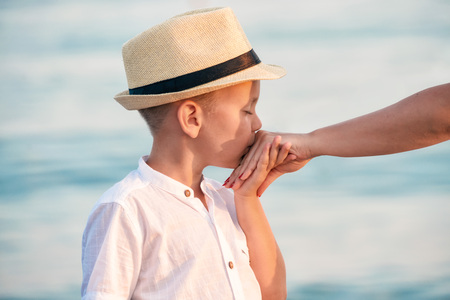 Boy in the hat, kisses the mother's hand on the sea coast.の写真素材