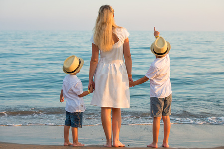 Family walking on the evening beach during sunset.Mother and two sons.の写真素材