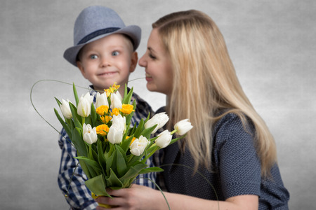 Small son gives his beloved mother a bouquet of beautiful tulips. Spring, concept of family vacation. Bouquet of flowers closeup.の写真素材