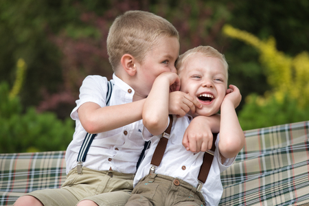The two brothers rest, telling secrets in his ear. Boys ride in the hammock.の写真素材