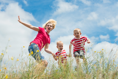 A young mother and two little sons having fun playing and jumping.の写真素材