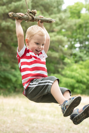 Little boy riding on a makeshift swing in the woods. ?の写真素材