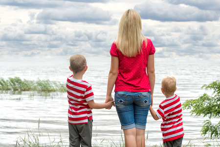 Mother and two sons watching the river. ?の写真素材