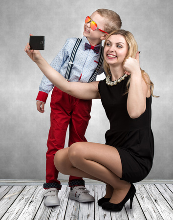 Young mother and son are photographed on a mobile phone, making selfie .Stylish, trendy, modern ?の写真素材