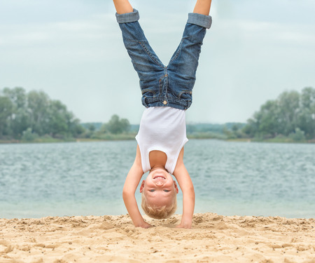 Little boy doing a handstand on the beach.Summer recreation and sports.