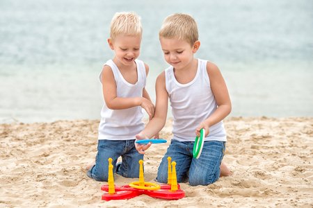 Two brothers are walking and playing on the beach. The game is a ring toss.の写真素材