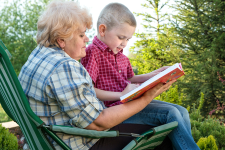 Grandmother and grandson reading a book outdoors.Family holiday with my grandmother.の写真素材