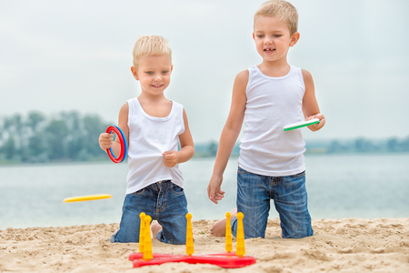 Two brothers are walking and playing on the beach. The game is a ring toss.の写真素材