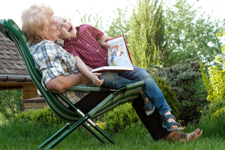 Grandmother and grandson reading a book outdoors.Funny stories. ?の写真素材
