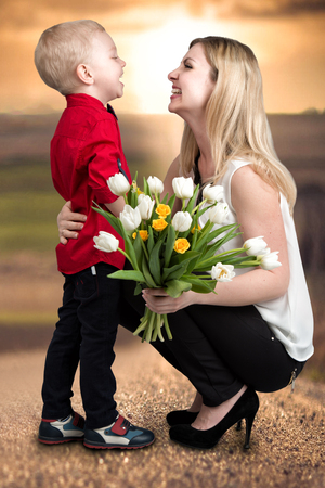 Small son gives his beloved mother a bouquet of beautiful tulips. Spring, concept of family vacation. Women's day.の写真素材