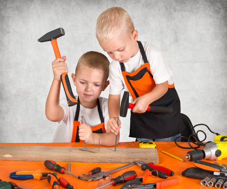 Two brothers working in the carpentry workshop. Hammer nails into a wooden plank.の写真素材