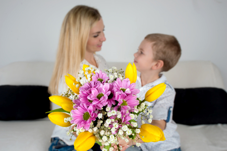 Son gives his beloved mother a beautiful bouquet of tulips. The concept of the celebration, women's day.の写真素材