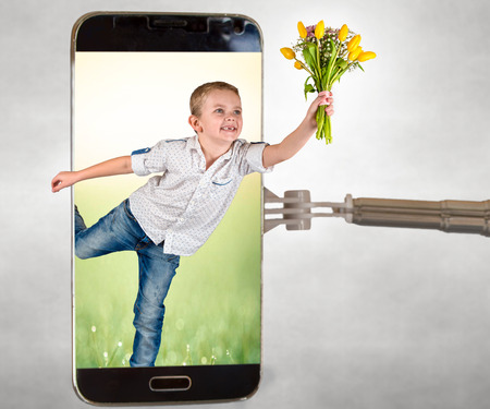 Spring surprise. The boy gives a bouquet of tulips through the phone screen. The concept of the holiday.の写真素材