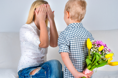 Son holding his bouquet of beautiful flowers for his beloved mother.The concept of the celebration, women's day.の写真素材