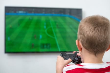 Boy with joystick playing video game at home.