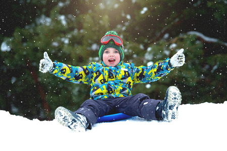 Boy sledding in a snowy forest. Outdoor winter fun for Christmas vacation.の写真素材
