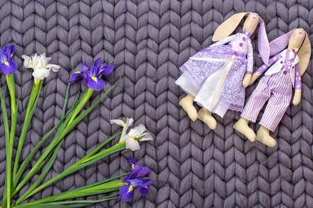 Couple loving hares handmade and bouquet of irises on a gray merino woolen blanket. Concept of...