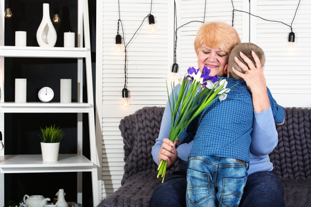Boy congratulates his beloved grandmother and gives her a bouquet flower.The concept of the celebration women's day.の写真素材