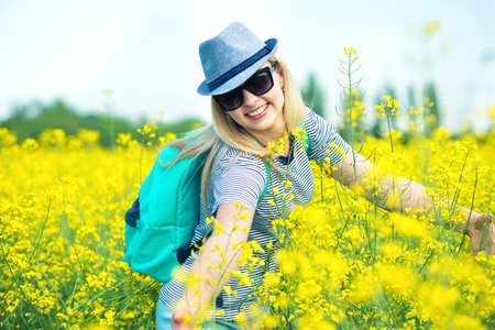 Young beautiful woman is walking along a flowering field on a sunny day.の写真素材