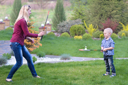 Mom teaches young son to play badminton.Active family vacation.