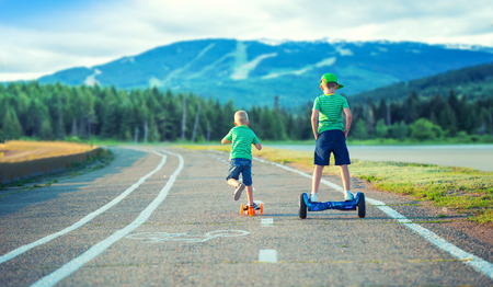 Two brothers compete who is faster.One goes to the balance board, and the second on the scooter.の写真素材