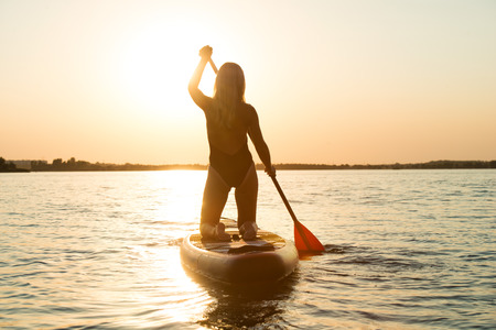 Young sexy woman swimming on stand up paddle board.Water sports, active lifestyle.の写真素材