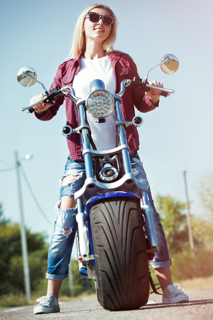 Girl biker riding a motorbike on an asphalt road.の写真素材