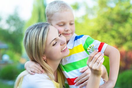 The little son gives his mother a bouquet of daisies.の写真素材