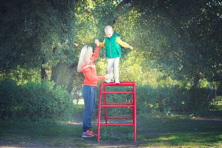 Mom helps the child to walk on the playground.の写真素材