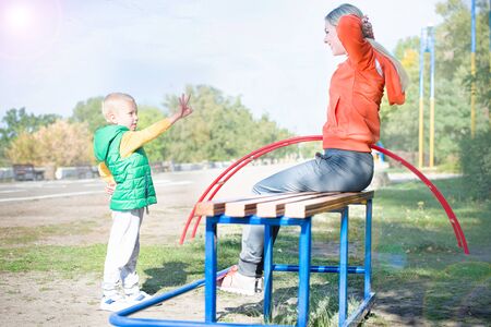 Mother and son does exercises on simulators on the street.の写真素材