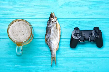 Vacation concept. Mug of cold beer with dried fish and a joystick.