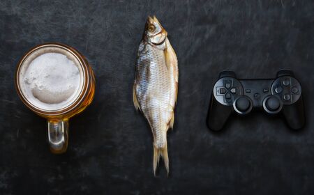 Vacation concept. Mug of cold beer with dried fish and a joystick.