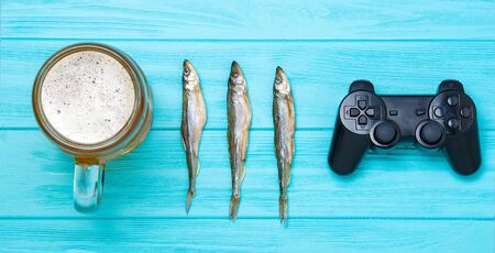 Vacation concept. Mug of cold beer with dried fish and a joystickの写真素材