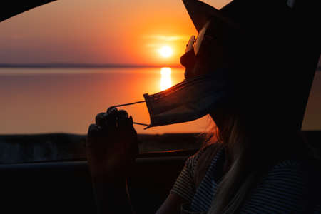 A girl sits in a car with a protective mask. The threat of a pandemic.Novel coronavirus - 2019-nCoV, COVID-2019 The concept of the virus.の写真素材