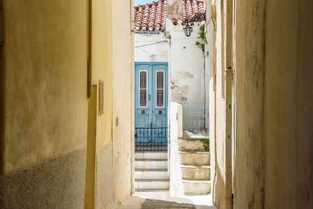 Narrow laneway in Chora old town Andros Island Greece with blue door at end.の写真素材