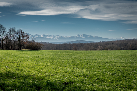 Snow capped mountains of the Midi Pyreneese set against green, grassy fields give the feeling of wide open spaces.の写真素材