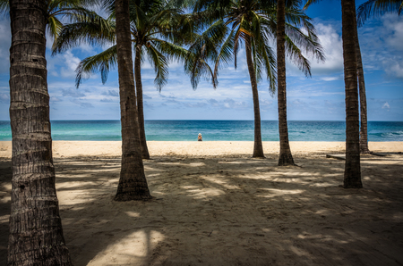 Lone girl at waters edge on a tropical beachの写真素材