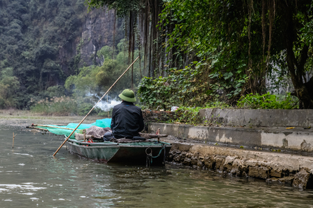 Fisherman smoking in his boat in Tam Coc Ninh Binh Vietnamの写真素材