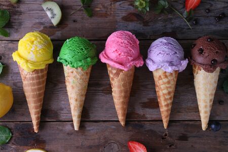 Variety of ice cream cones on wooden table.